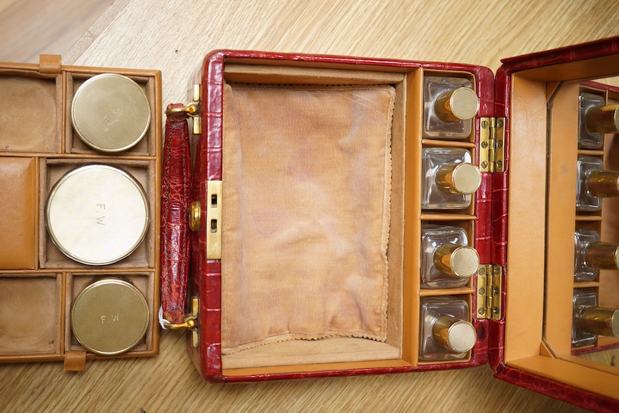 A red stained crocodile skin two layer vanity case, fitted with brass topped bottles and pots, case 22cm wide x 13.5cm high. Condition - handle has pulled away one side and needs re stitching